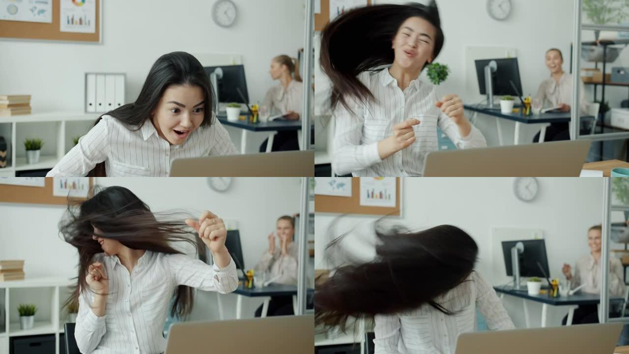 快乐的亚洲女人用笔记本电脑工作，然后享受成功跳舞的乐趣