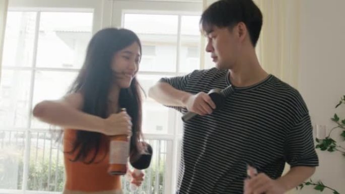 年轻的亚洲女性和男性喝啤酒跳舞玩得开心。