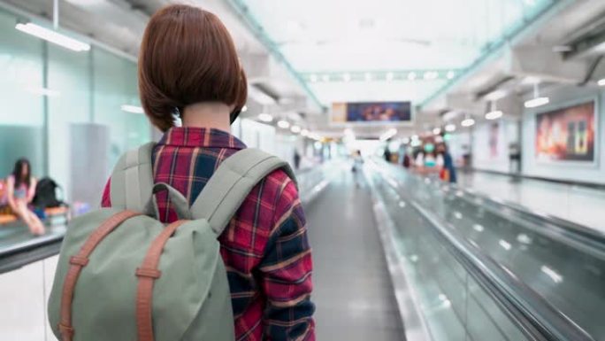 在机场自动扶梯上新型冠状病毒肺炎时戴着防护面罩的亚洲女性游客