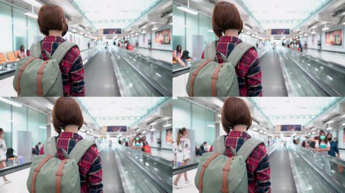 在机场自动扶梯上新型冠状病毒肺炎时戴着防护面罩的亚洲女性游客