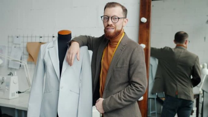 男性时装设计师的慢动作肖像站在工作室附近的假人穿着新的手工服装
