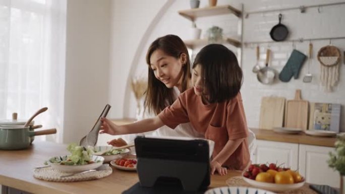 母亲抱着女儿在厨房做饭