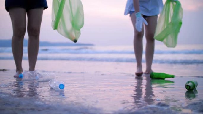 一群年轻女子在海滩上捡塑料瓶，回收概念