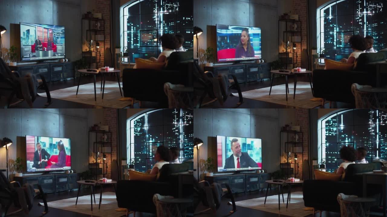男女朋友坐在家里的沙发上，在电视机上观看深夜新闻电视节目。脱口秀屏幕: 主持人接受嘉宾采访。恋爱中的