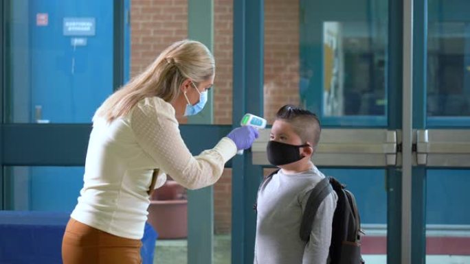 戴着口罩的孩子，在学校入口处检查温度
