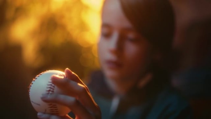 一个年轻的体育迷在家中拿着白色棒球球的特写肖像。兴奋的男孩看着球，把球转了过来。在怀旧复古的童年概念