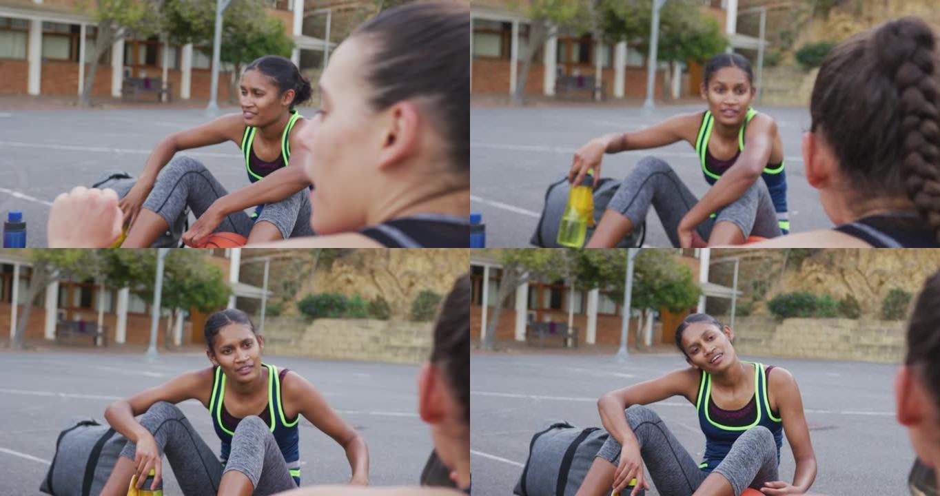 多元化的女子篮球队坐在地上聊天