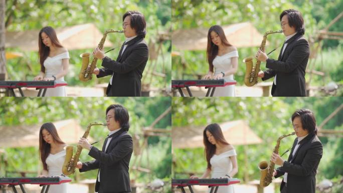 亚洲中国夫妇萨克斯管键盘演奏家乐队在农村地区表演正装练习