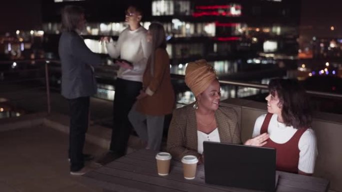 商务人士，在发展，社交或团队建设中，在办公楼的屋顶上聊天和过夜。妇女，笔记本电脑或在阳台上与团体，平