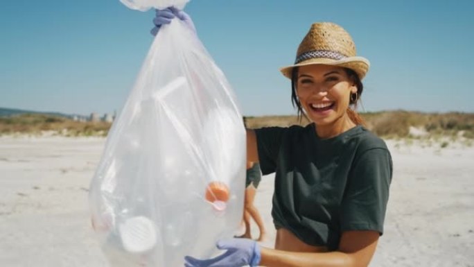 一位戴着帽子的年轻黑发女志愿者的慢动作在镜头前微笑着，满足于在大海的海滩上捡起塑料垃圾以保护环境。
