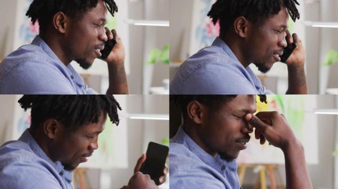 压力大的非裔美国男艺术家在art studio的智能手机上聊天的特写