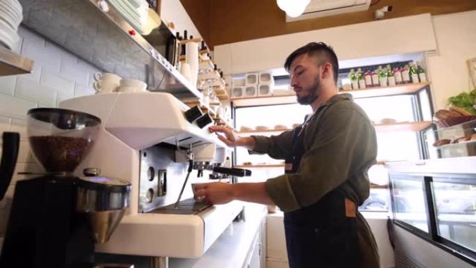 年轻的男咖啡师在咖啡店准备浓缩咖啡