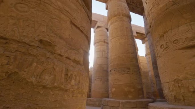 雄伟的柱子上有古埃及的图画，太阳从柱子后面出来。埃及卢克索的卡纳克神庙
