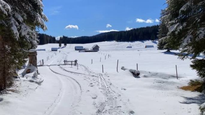 在阳光明媚的冬日，通往被雪覆盖的雄伟山脉高原的小路