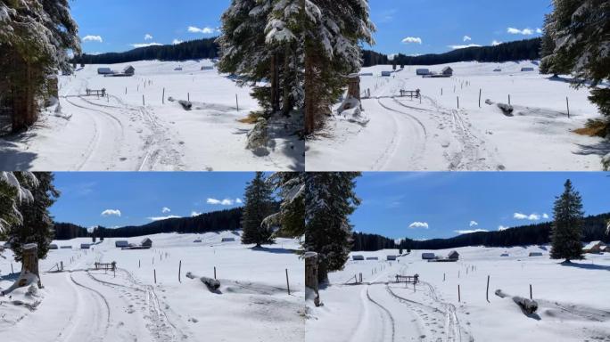 在阳光明媚的冬日，通往被雪覆盖的雄伟山脉高原的小路