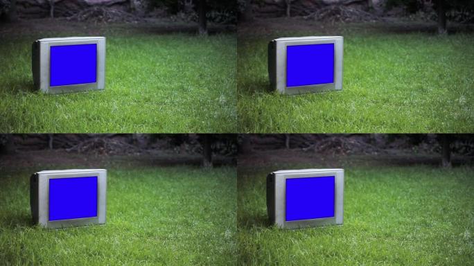 绿草地上有蓝屏的旧电视。放大。