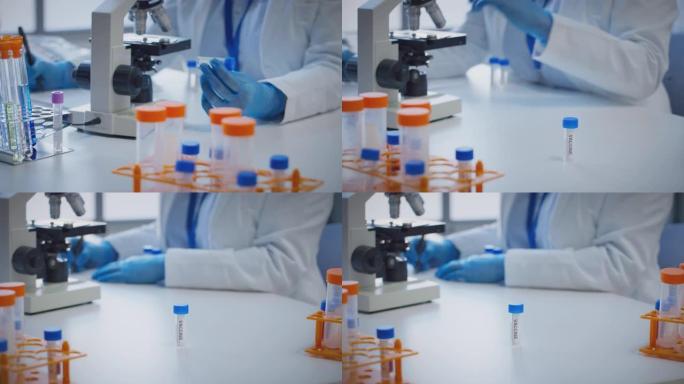 近距离观察实验室工作人员使用显微镜进行研究，持有标有疫苗的试管