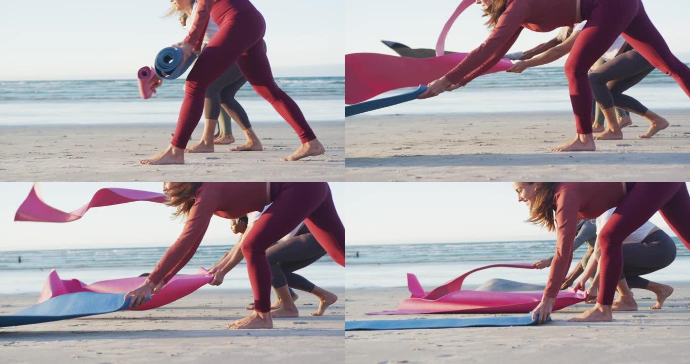 一群不同的女性朋友在海滩练习瑜伽前准备瑜伽垫
