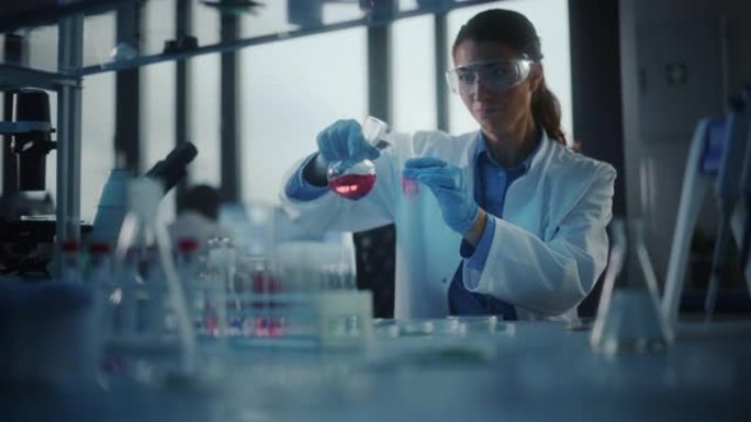 美丽的女科学家戴着护目镜，在实验室的试管中混合化学物质。年轻的专业微生物学家在现代实验室工作，拥有技