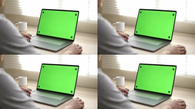 一个女人的特写镜头使用带有绿色模拟屏幕的笔记本电脑