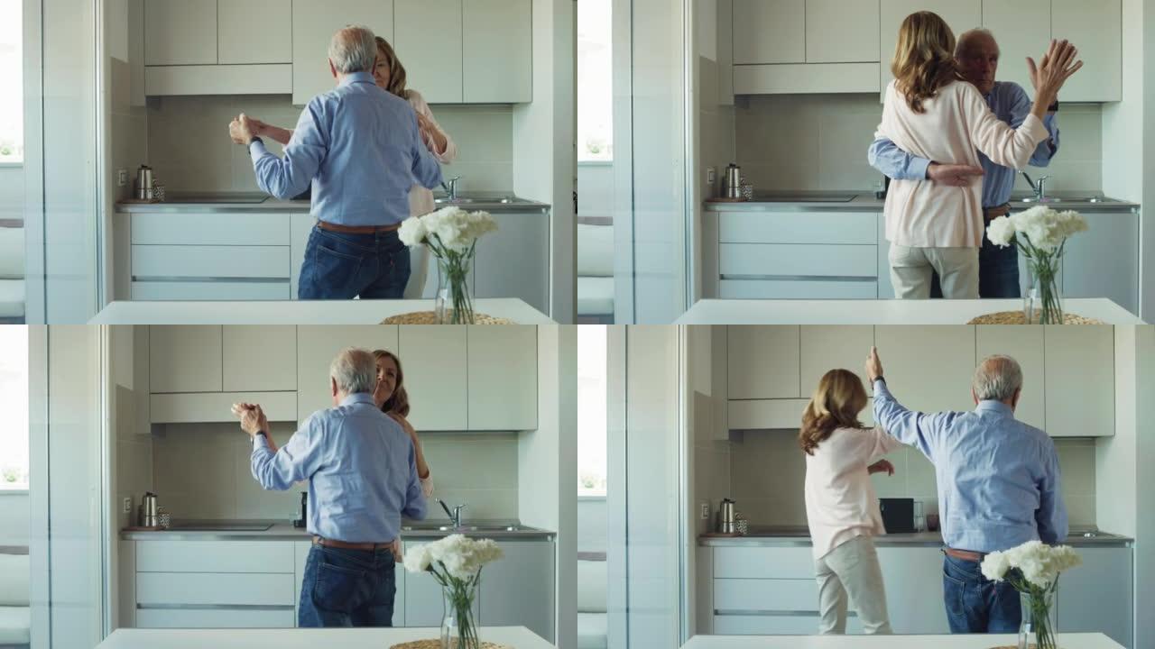 在爱情中快乐成熟的高级夫妇的电影拍摄是享受时间在一起，跳舞庆祝他们在家里的厨房永恒的爱情。概念: 爱