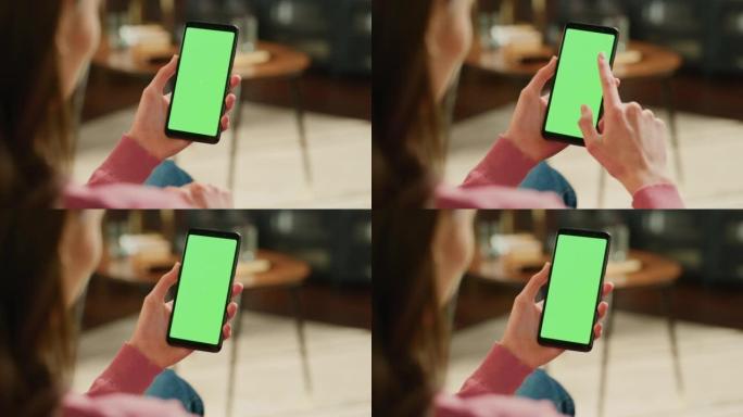 带有绿屏模拟显示的智能手机上的女性手点击显示屏和滚动供稿。女性在家休息，在移动设备上查看社交媒体。特
