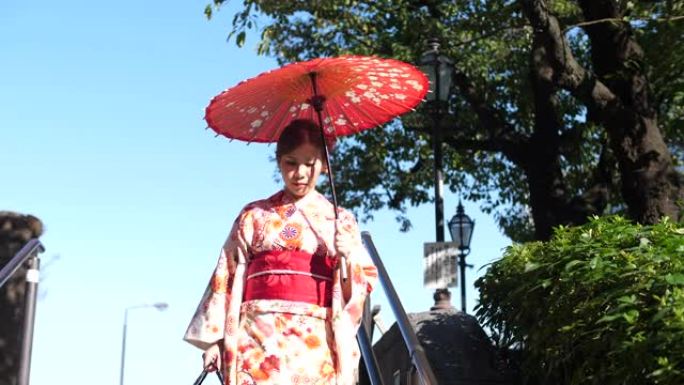 亚洲女子穿着传统日本和服礼服，手持红纸伞