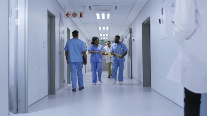 讨论中的非裔美国男女医生在繁忙的医院走廊中行走