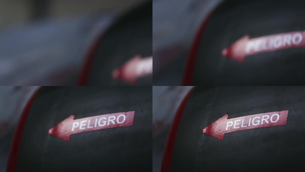 红色和白色箭头标志，在阿根廷战斗机的后端写着西班牙语单词DANGER。特写。