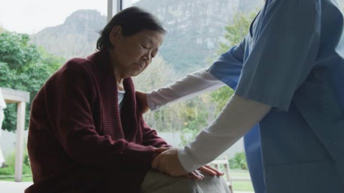 微笑的亚洲女医生安慰资深女病人并在手术中交谈