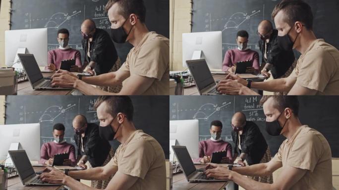 戴口罩的男子在使用笔记本电脑