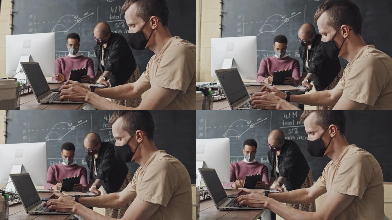 戴口罩的男子在使用笔记本电脑
