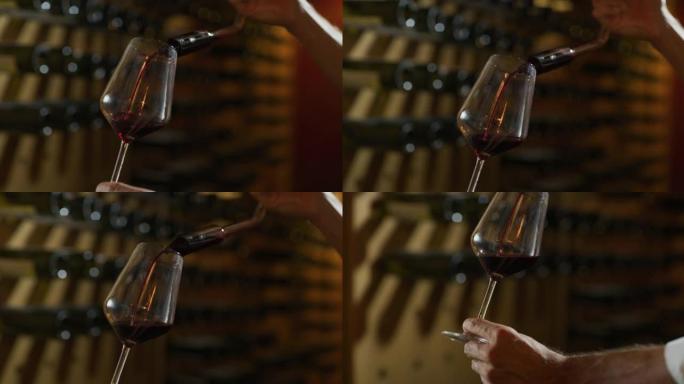 近距离拍摄酿酒师或侍酒师正在将红酒倒入透明玻璃杯中，以品尝风味并检查酒窖中的质量。