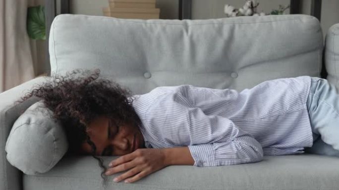 非洲妇女感到疲倦摔倒在家里的沙发上