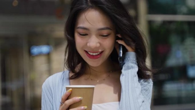 迷人的年轻亚洲商务女士走在城市街头用手机聊天放松快乐办公室女士在城市慢动作