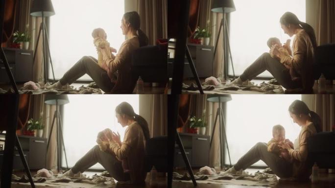 母亲和婴儿的亲密时刻: 一个刚成为母亲的亚洲妇女的真实镜头，早上在家与她可爱的孩子玩耍。母亲和婴儿的