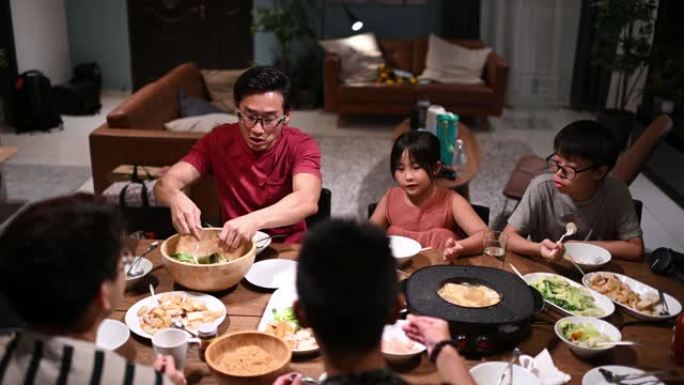 亚洲华人家庭和朋友在家里吃晚餐，吃传统的中国汽船菜肴