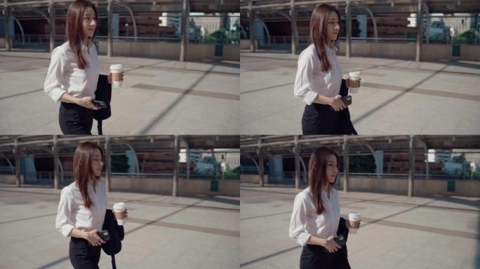 自信的年轻女商人在穿越城市时喝咖啡