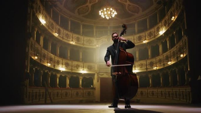 男性大提琴家的电影镜头正在经典的剧院舞台上独奏大提琴，并带有戏剧性的灯光