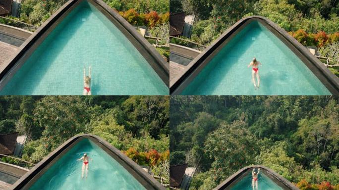 顶视图性感女人在热带酒店水疗中心无限泳池游泳，丛林景观享受异国情调的暑假4k奢华生活方式