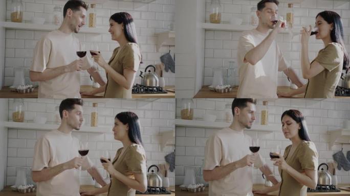 年轻女子与男友站在公寓厨房里聊天的酒杯