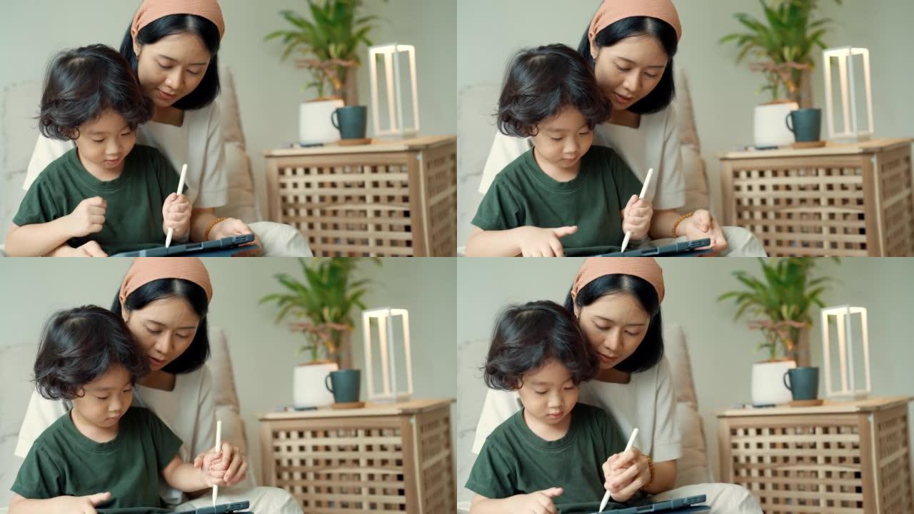 亚洲单身母亲花时间和儿子在数字平板电脑上画画。