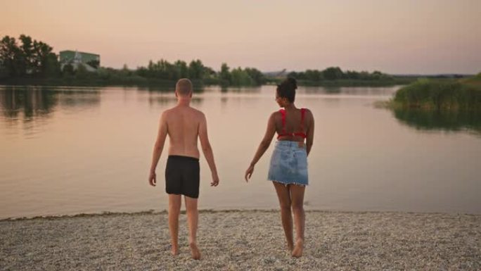 SLO MO年轻夫妇在黄昏时走进湖中