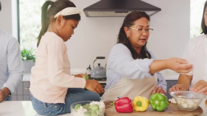 一家人一起在厨房做饭。兄弟姐妹帮助他们的母亲在他们的现代家庭中准备有益健康的营养食谱。父母教女儿如何
