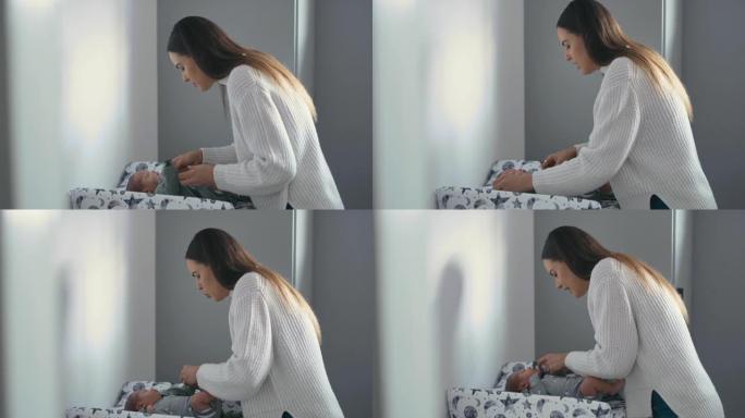 4k视频片段，一名妇女在换衣桌上脱下婴儿的衣服