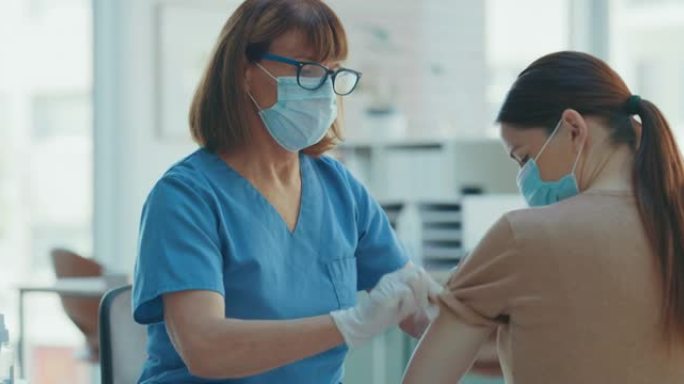 4k视频片段，一名护士在给她的病人注射了Covid疫苗后给她贴了创可贴