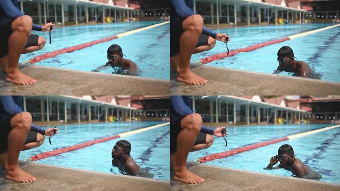 亚洲中国私人教练在运动训练期间在泳池边向学生展示秒表时间记录