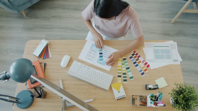女性设计师为移动应用选择颜色并在办公室使用pc的高角度视图
