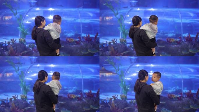 母亲带着他的婴儿在水族馆里看着鱼