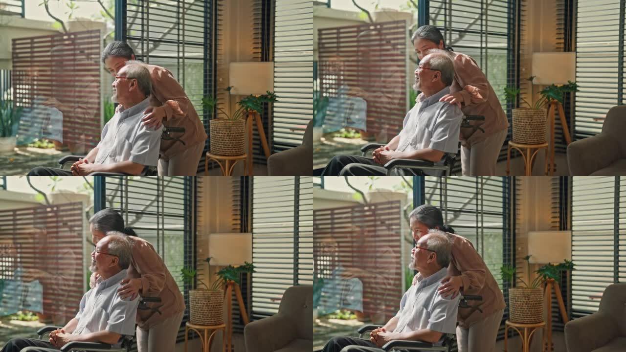 快乐的高级女人在室内轮椅上拥抱丈夫。